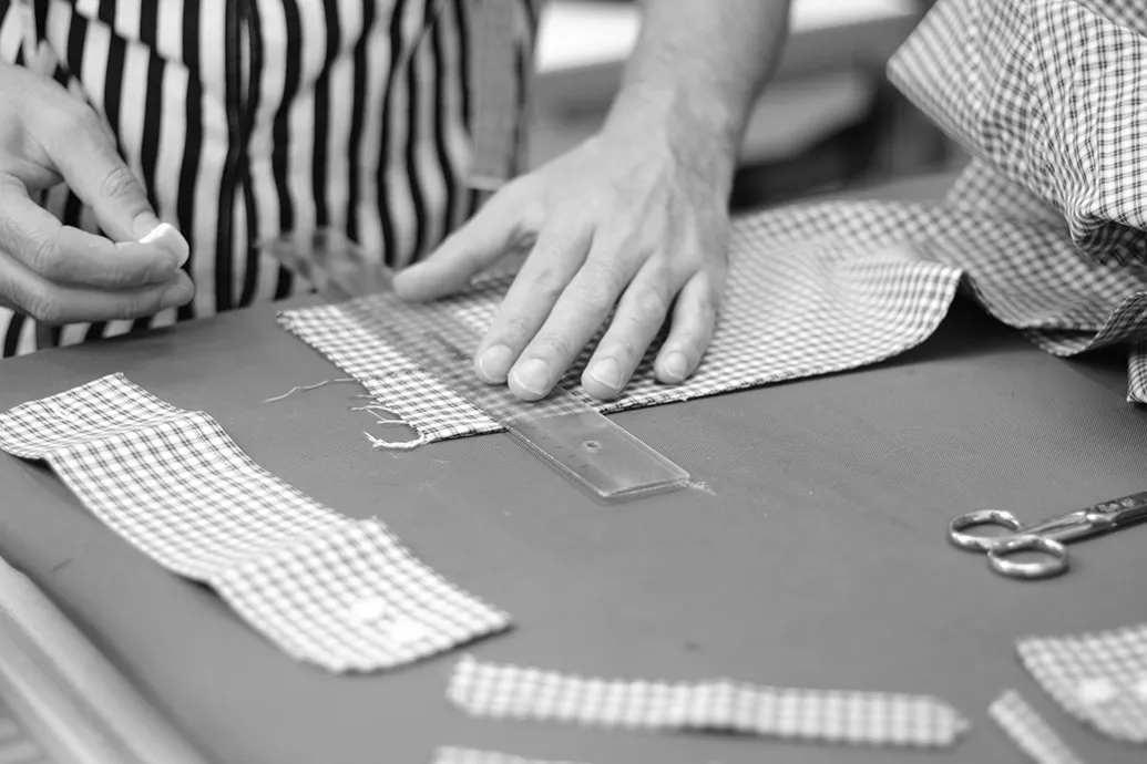 Stoff wird auf dem Zuschnittisch mit Lineal angezeichnet